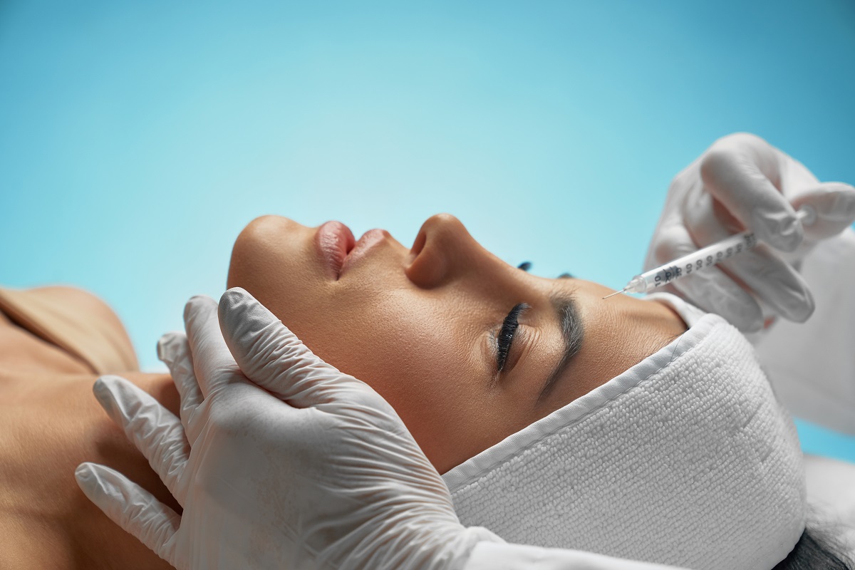 woman lying down while receiving a Botox injection in her forehead